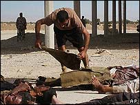 Iraklı asker, intihar saldırısında öldürülen polis adaylarının üzerini örtüyor