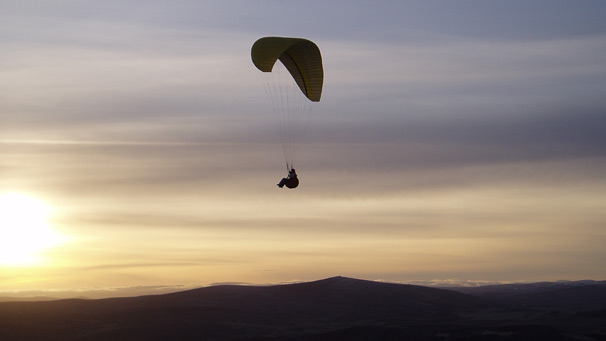 Silhouetted paraglider in flight