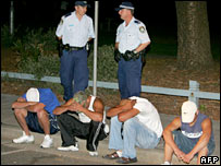 پولیس گرفتار نوجوانوں کے پاس کھڑی ہے 