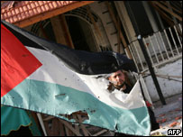 Palestino do Hamas atrás de bandeira danificada por ataque a escritório do primeiro-ministro Ismail Haniya