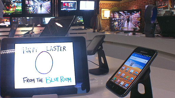 View of mobile devices on a desk in the Blue Room, with a corner of a living room and a car dashboard in the background.
