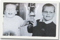 Rees Bowdler yn dal cwpan y diweddar gynghorydd L M Pritchard gyda Meurig, ŵyr Mr Pritchard.