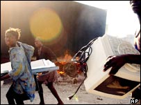 Haitianos carregam produtos saqueados no porto de Saint Marc