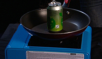 an empty drinks can on a fry pan on a gas stove.
