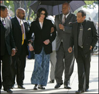 Jackson chega ao tribunal de paletó, pijama e chinelo, amparado por seguranças