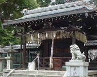 Lion statues guarding the doorway to a shrine, with stone lanterns and ceremonial paper streamers visible