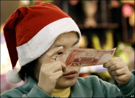 A shop clerk with a Santa hat on checks a 100-Chinese renminbi note Wednesday, Dec. 3, 2008, in Shanghai, China. (AP Photo)