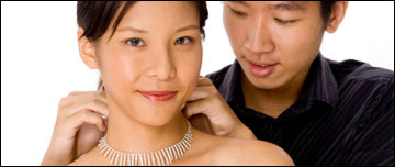 A man puts a necklace on his wife