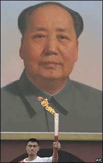 Yao Ming com tocha em frente a cartaz de Mao