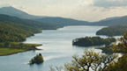 Colour view across the broad expanse of Loch Tummel, with hills around and peak of Schiehallion behind.