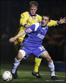 Michael Frew of King's Lynn challenges Oldham's Neil Eardley in FA Cup action three years ago