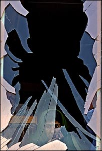 زن افغان در پشت شیشه شکسته یک ساختمان در کابل