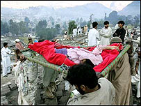 Muži vynášejí člověka zabitého při zemětřesení