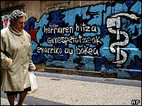Mulher passa em frente a mural apoiando o ETA