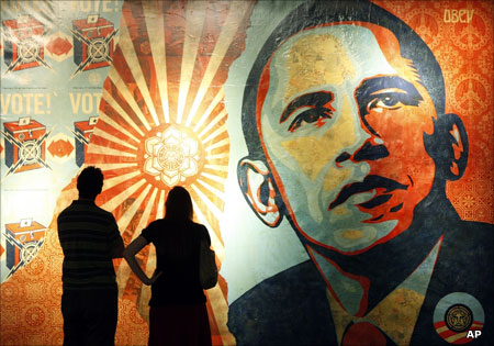 A couple standing in front of Shepard Fairey's Obama Hope mural