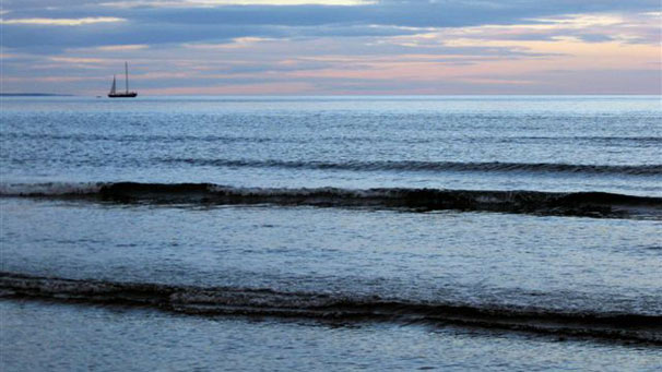 A boat sailing away into an early sunset