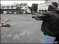 Homem aponta para um corpo na rua em Kinshasa