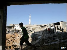 Một người Palestine đi ngang qua đống đổ nát