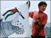 Palestino empunha bandeira mostrando a destruição da barreira israelense