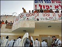 Colonos ortodoxos rezam em frente a sinagoga onde se entrincheiraram no assentamento de Kfar Darom