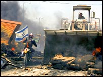 Yıkılan yerleşim birimi arasından geçen bir motosiklet