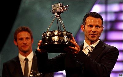 Ryan Giggs muestra el trofeo. Al fondo observa Jenson Button