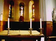 Altar at the front of a church, covered in a white cloth with candlesticks