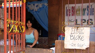 Филиппинская продавщица кубиков льда на фоне вывески ICE BLOKE FOR SALE