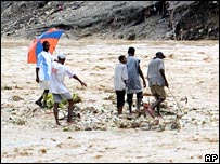 Haitianos passam por área inundada após passagem da tempestade Alpha
