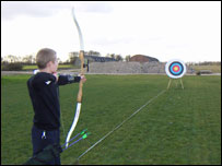 Boy firing arrow at target