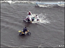 Un grupo de personas trata de cruzar una carretera inundada.