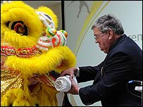 Cllr Jeremy Pembroke receives the Olympic flag from a Chinese lion