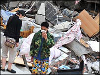 Morador cobre o nariz em meio a ruínas em Beichuan