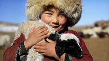 Bachgen yn anialwch Gobi, Mongolia, gyda'i afr anwes © Timothy Allen