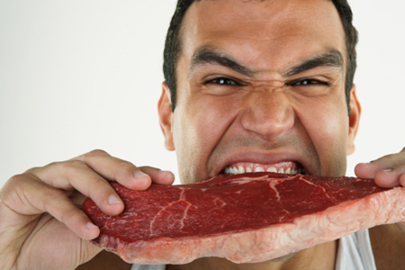 Man biting into raw steak