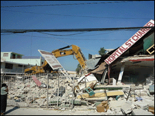 A crane parked by a hospital sign and rubble.