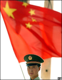 Một công an Trung quốc đứng trước cờ tổ quốc