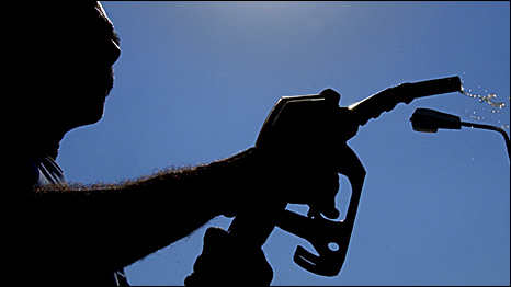 A man in silhouette fills up at a petrol station