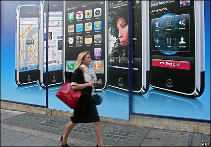 A woman walks past an iPhone advert in central London