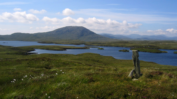 A view of a standing stone, with lochs in the distance