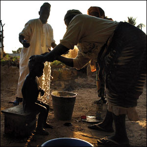 A child having the blood washed off his head after a scarification