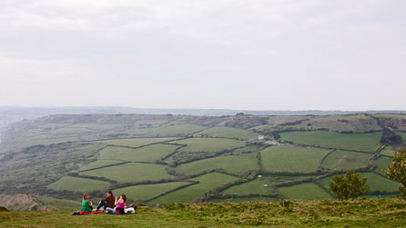 Teulu yn eistedd ar ben bryn