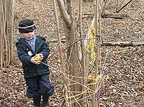Little boy twisting string around a tree.