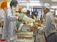 Sikh men serve food inside a Langar