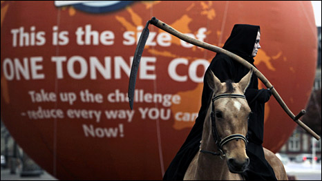 A man dressed as death rides past a balloon indicating the volume of one tonne of carbon dioxide, outside parliament in Copenhagen