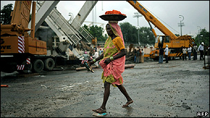 An Indian worker walks in front of a collapsed bridge next to the Jawaharlal Nehru Stadium