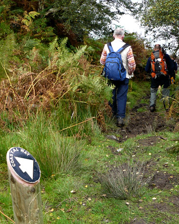 Walkers passing an Arran Coastal Path sign