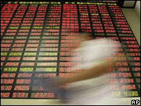 Passante em frente a quadro com resultados da bolsa de Shanghai (foto de arquivo)