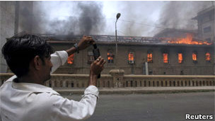 A man taking a picture of a burning building with his phone