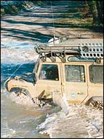 Landrover driving through river.